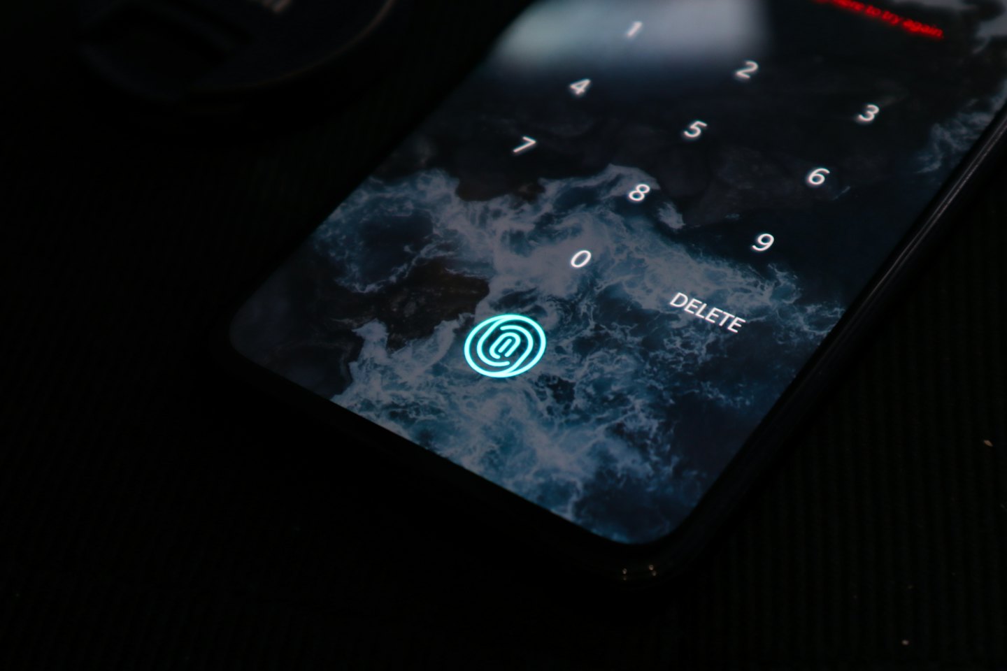 Blocco schermo di uno smartphone con scanner di impronte digitali e sfondo astratto.