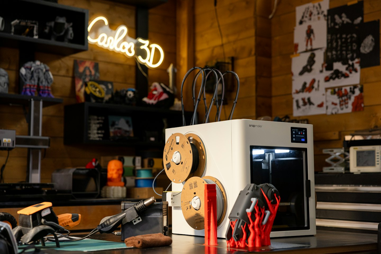 Una moderna stampante 3D crea un oggetto rosso su un banco da lavoro.